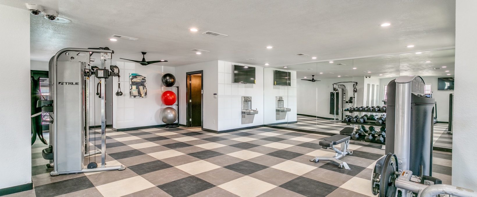 a gym room with a tiled floor and a black and white checkered floor at The  Holden
